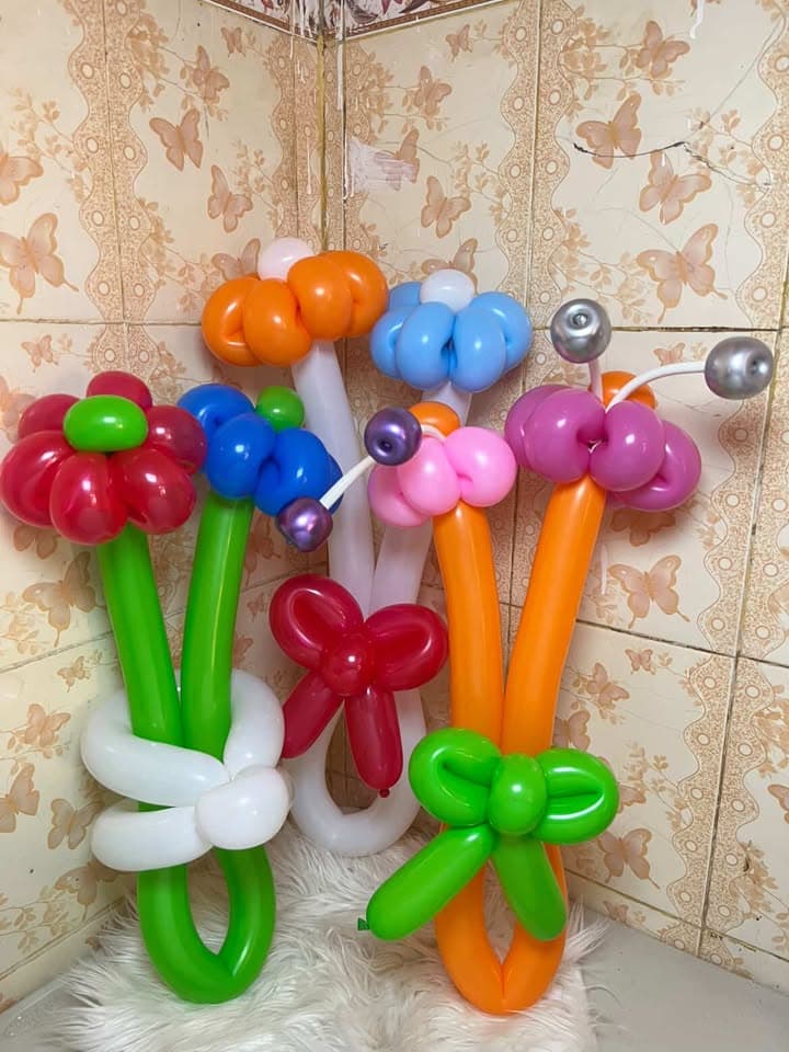 Tiga buket bunga balon warna-warni berjajar di depan dinding