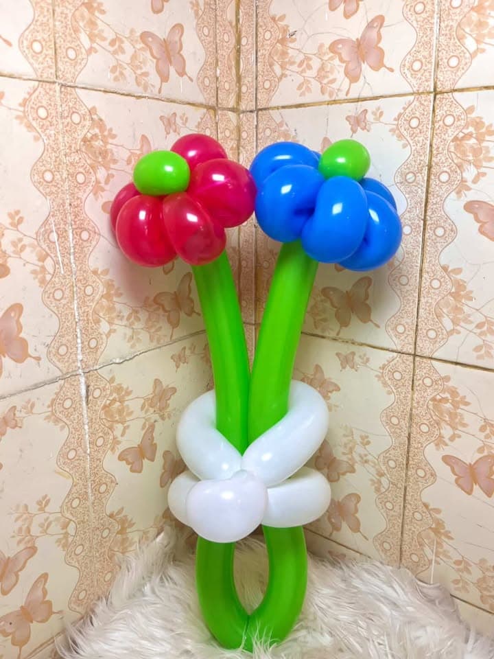 Bunga balon merah dan biru bertangkai hijau dengan pita putih